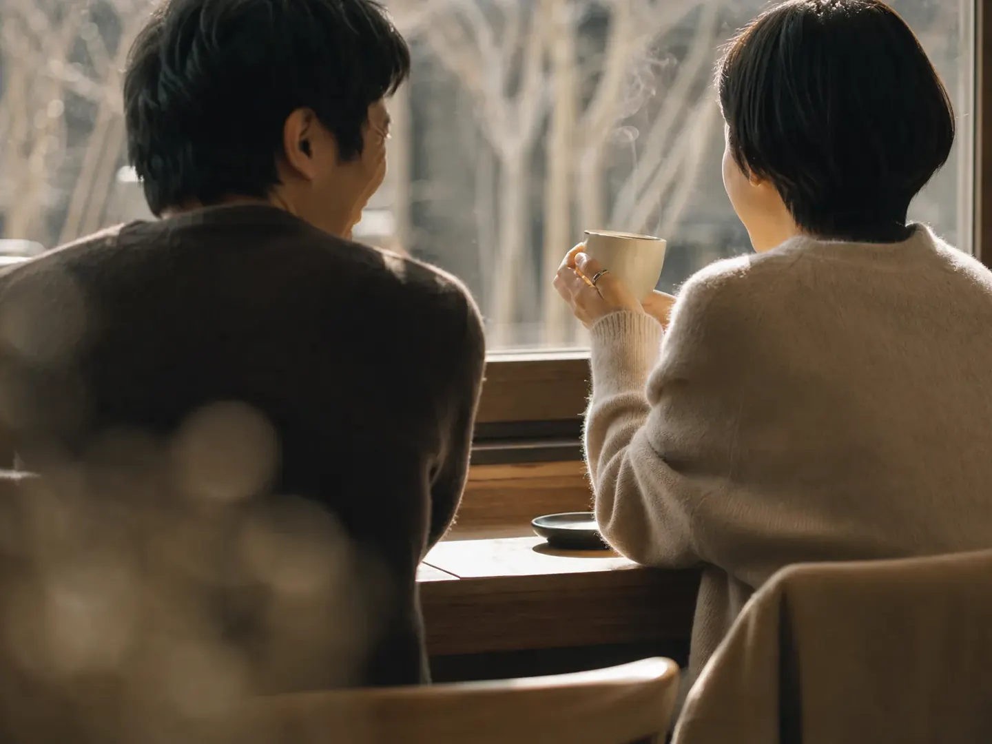 窓際の席でコーヒーを飲む二人